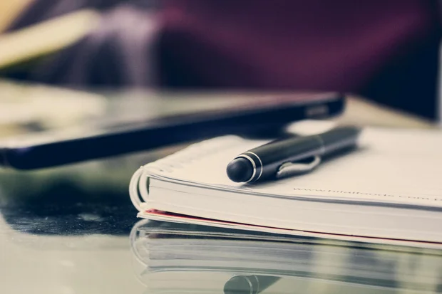 Photo représentant un cahier, un stylo et un portable