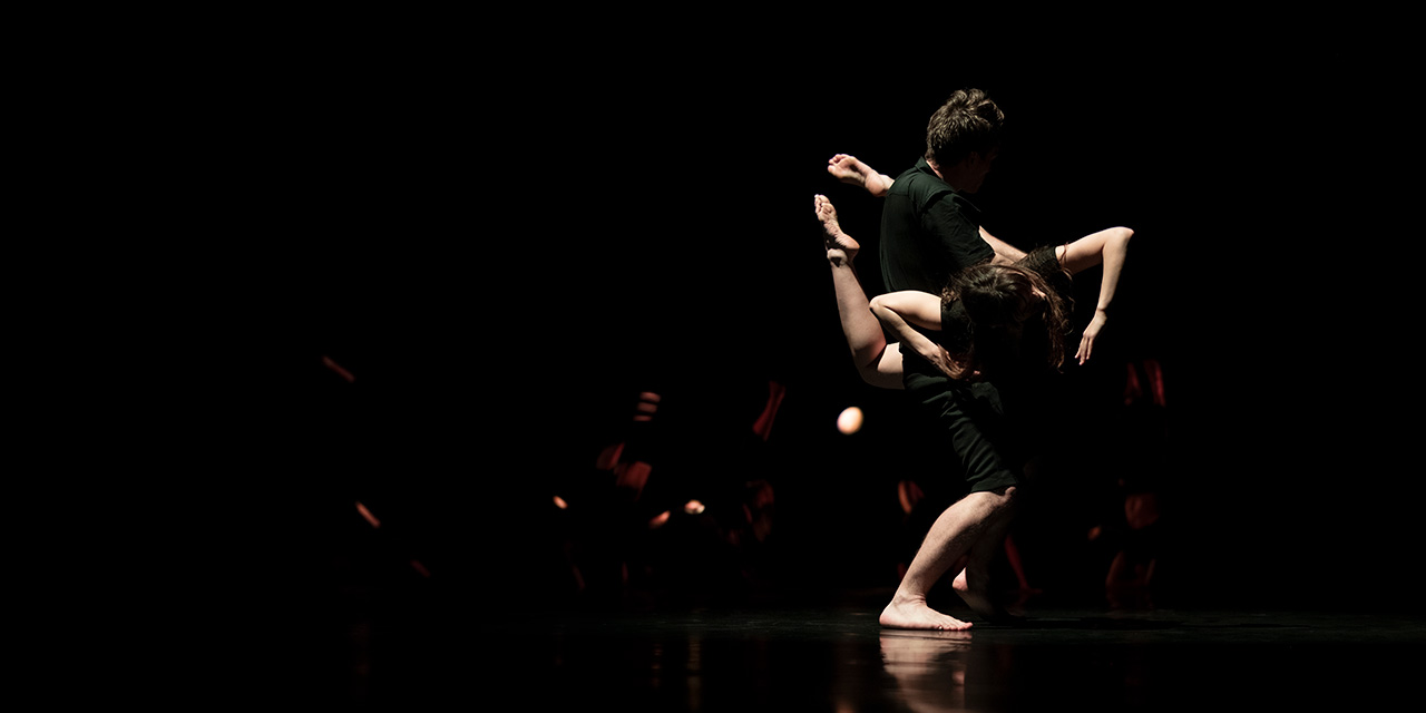 Un danseur et une danseuse vêtus de noir entrelacés