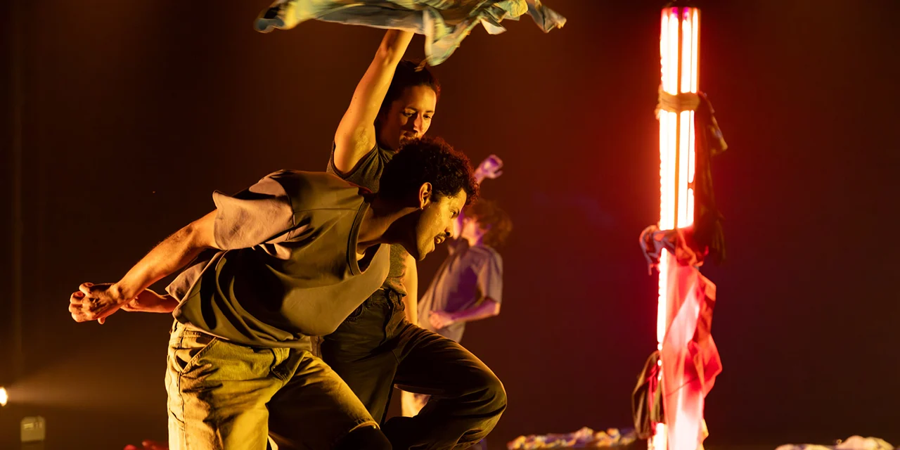 Un danseur et une danseuse en mouvement dans une scénographie composée de néons et de tissus