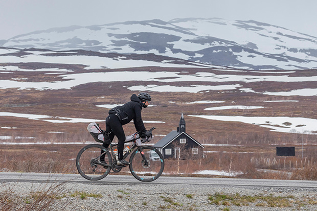 Nathalie Baillon, sur son vélo sur la route devant des pentes enneigées