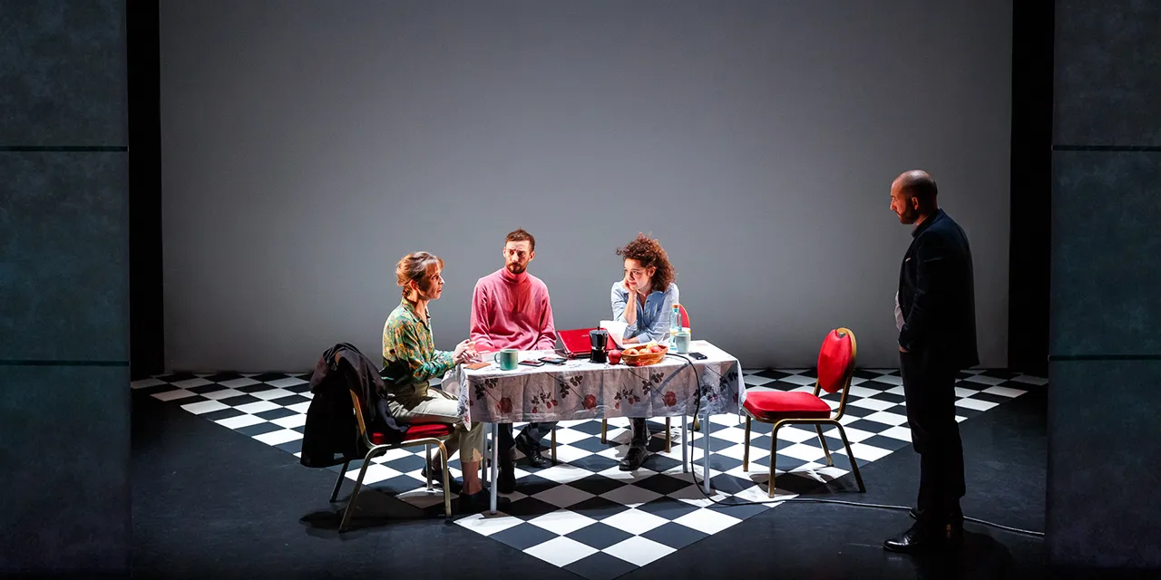 3 interprètes sont en discussion, assis autour d'une table. Un quatrième les regarde.