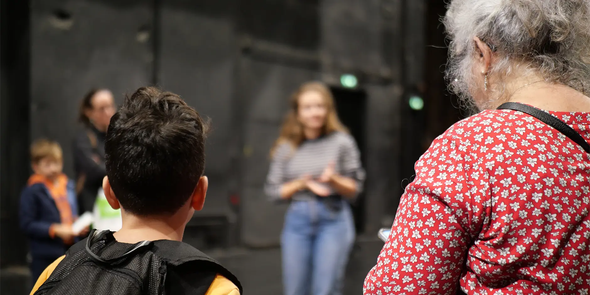 Des enfants et une adulte de dos qui écoutent une présentation