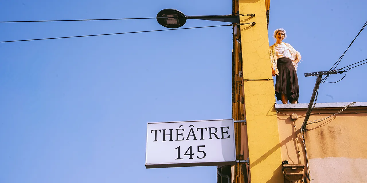 Le circassien Léo Manipoud se tient debout en costume sur le toit du Théâtre 145.