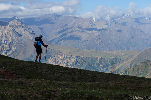 Un homme avec un sac de randonnée devant une chaine de montagne