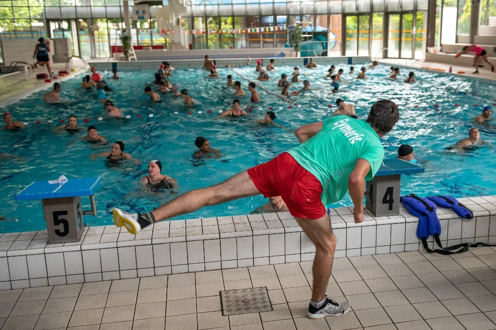 Photo d'un maitre nageur donnant un cours d'aquagym à de nombreux participant dans la piscine des dauphins