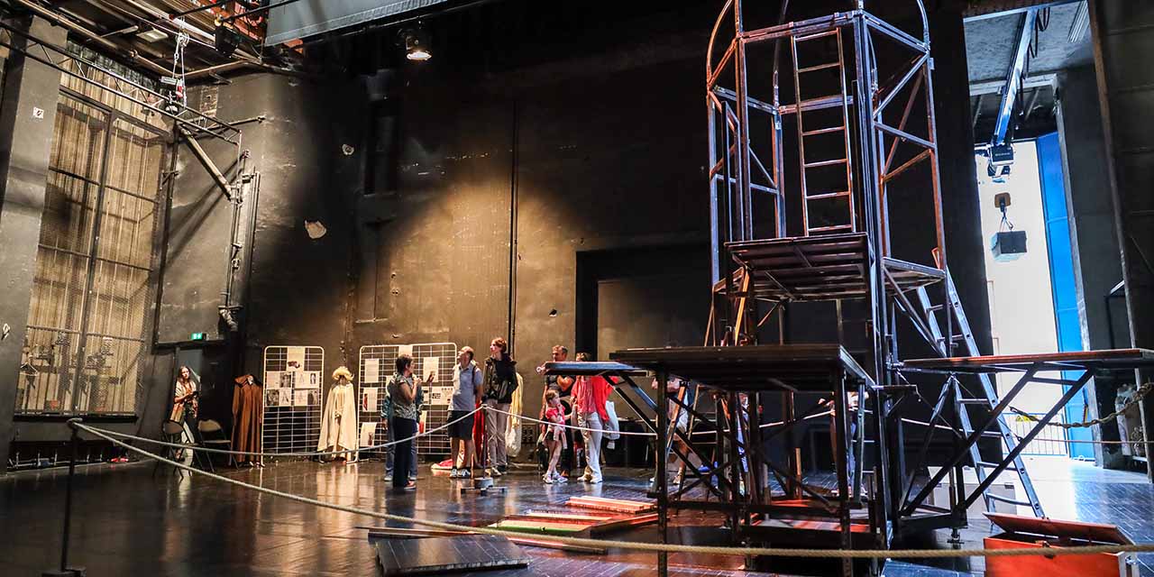 Un groupe de personnes se trouve sur le plateau du Grand Théâtre et admire une structure d'un décor de spectacle
