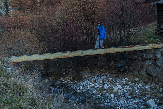 Une homme marche sur une poutre en ferraille au dessus d'un lit de rivière