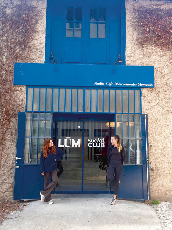 Les gérantes posent devant une grande porte en fer et en verre.