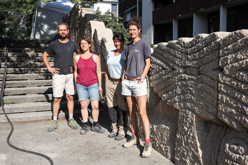 Les quatre restaurateurs posent devant le mur sculpté.