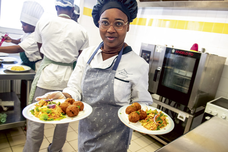 Une femme emporte deux assiettes prêtes à être servies.