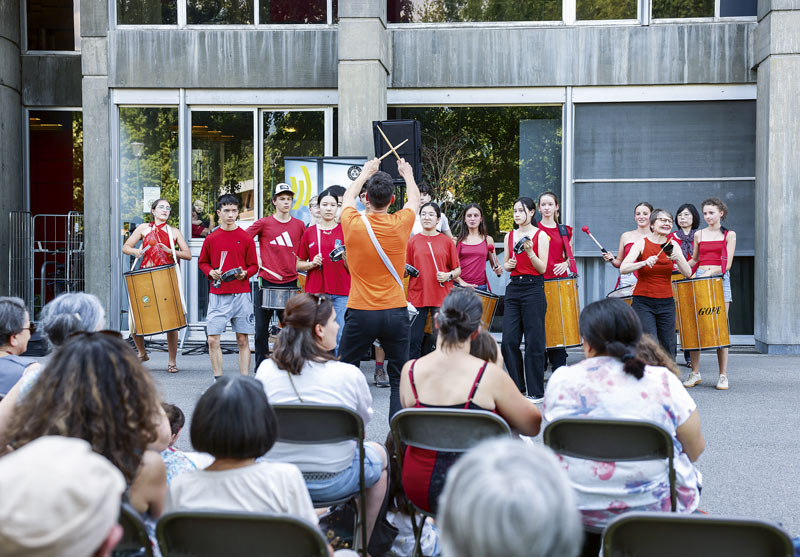 Un groupe de jeunes musiciens jouent devant le conservatoire.