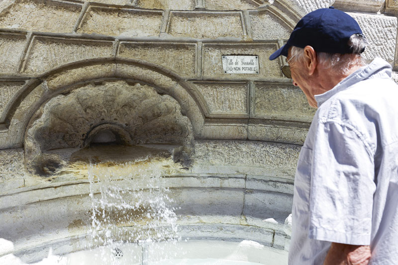 Un homme regarde l'eau couler dans une fontaine.