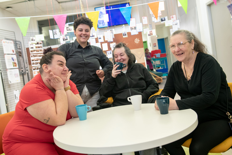 Quatre femmes posent autour d'une table avec des cafés.