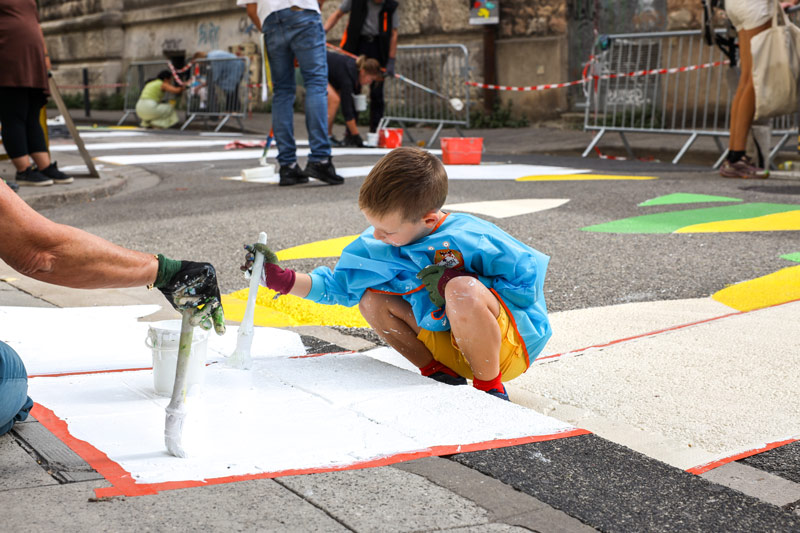 Un enfant peint des motifs sur la route.
