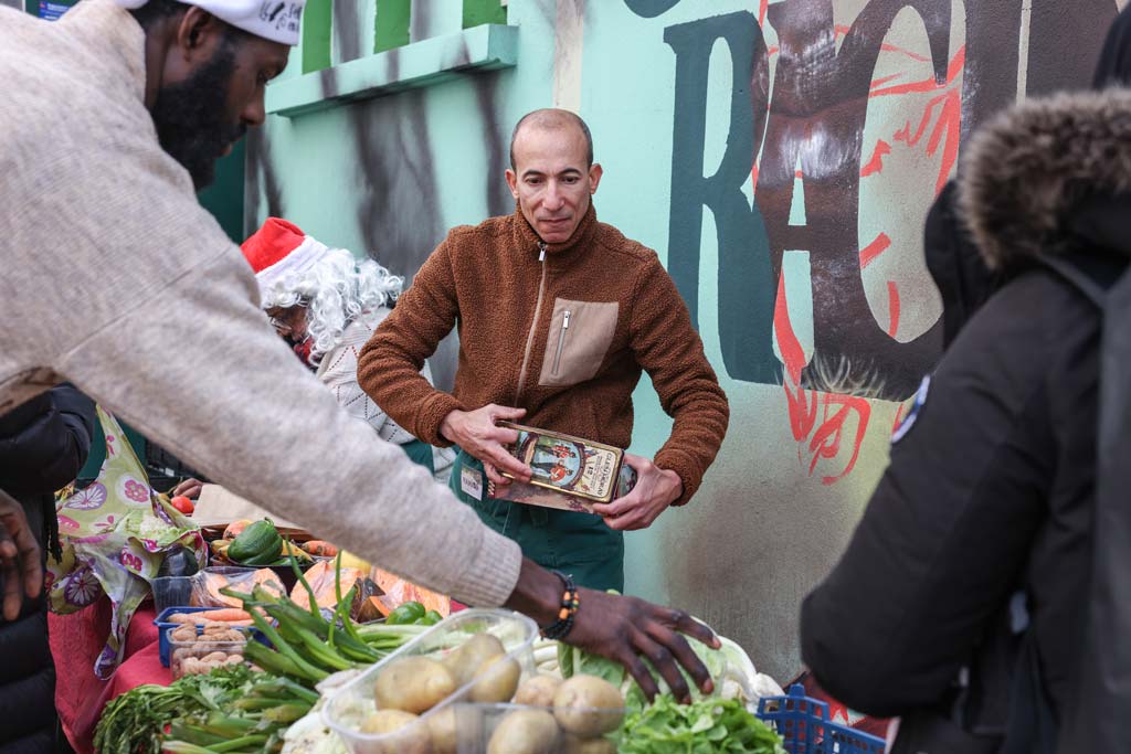 Des personnes se servent autour d'un étal de légumes.