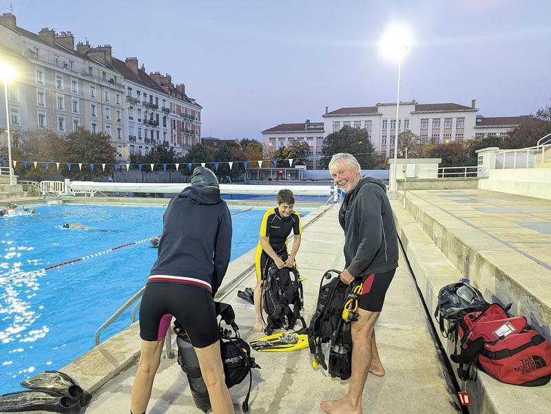 Trois personnes préparent des bouteilles d'oxygène pour leur entraînement.