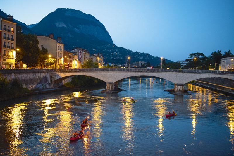 Des canoës descendent l'Isère de nuit.