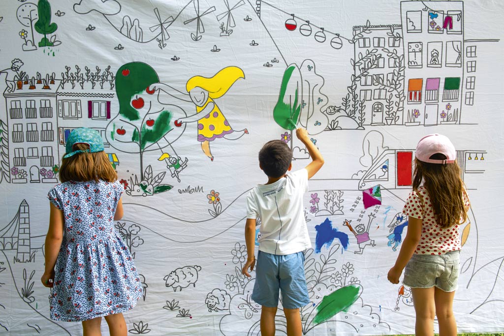 Des enfants colorient une fresque géante. 