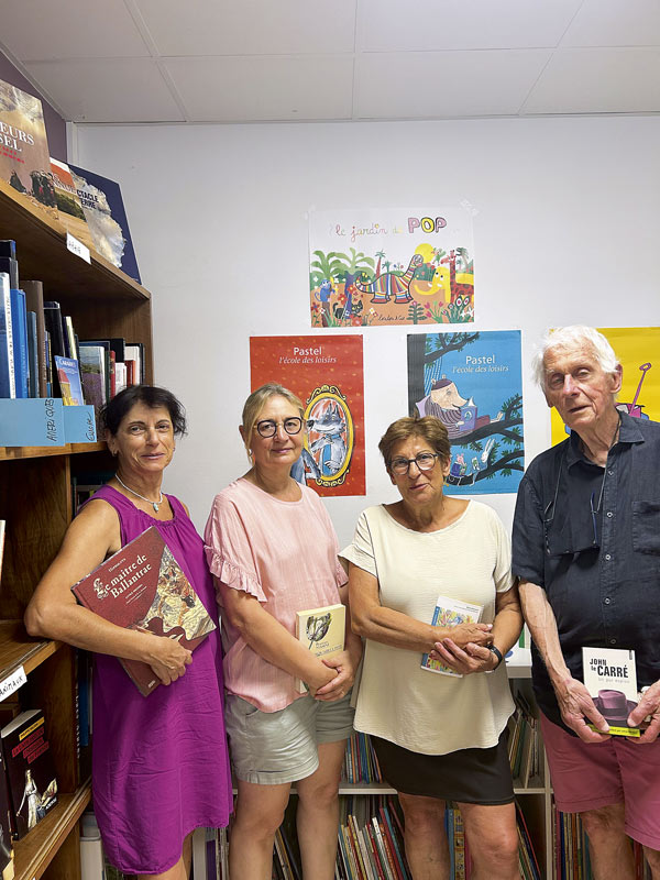 Quatre bénévoles posent dans la bibliothèque.