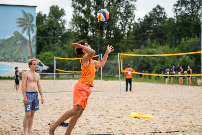 Une personne tape dans une balle de volley. Le terrain est fait de sable.
