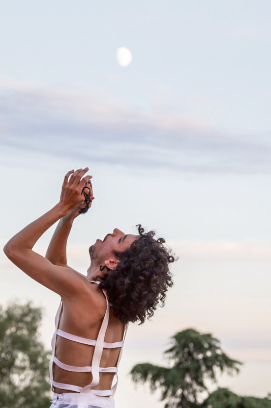 Un homme danse au coucher du soleil. La lune commence à apparaître.
