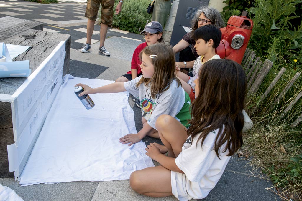 Des enfants réalisent des pochoirs sur l'espace public. 