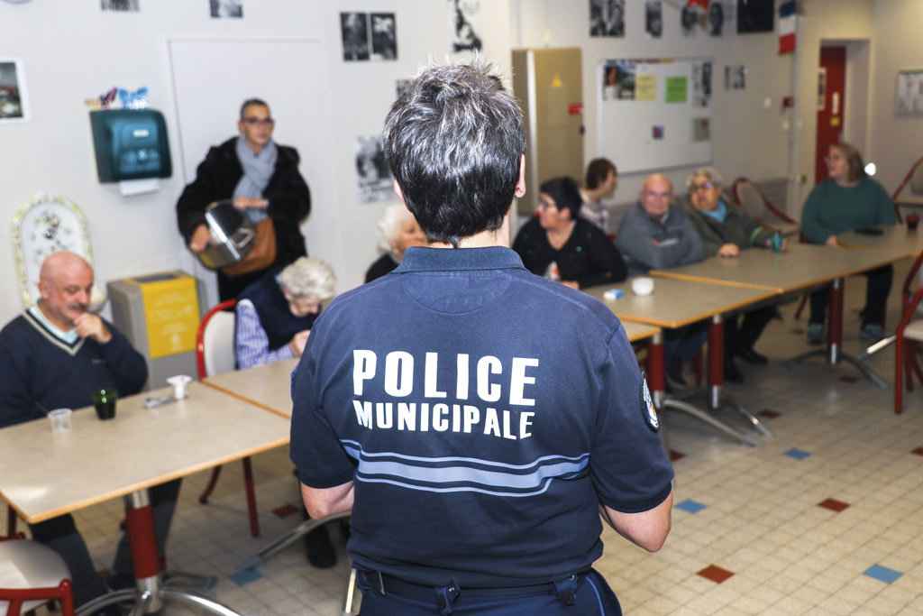 Une policière informe des personnes âgées.