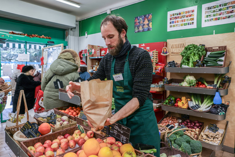Un employé remplit un sac de légumes.