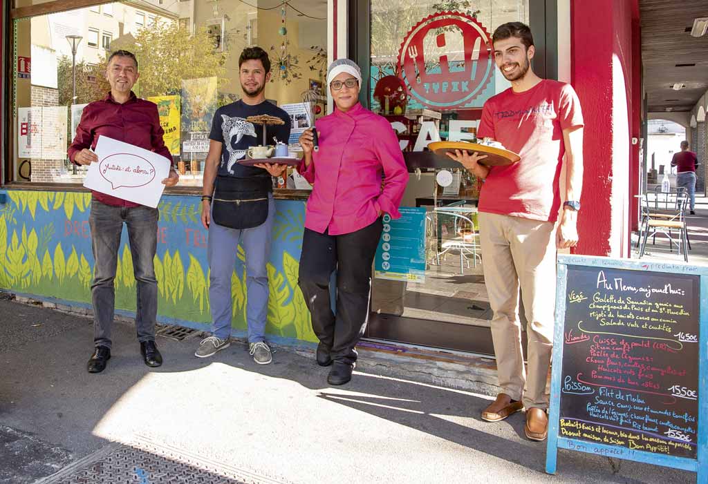 L'équipe pose devant le restaurant avec un panneau "Autiste, et alors ?".