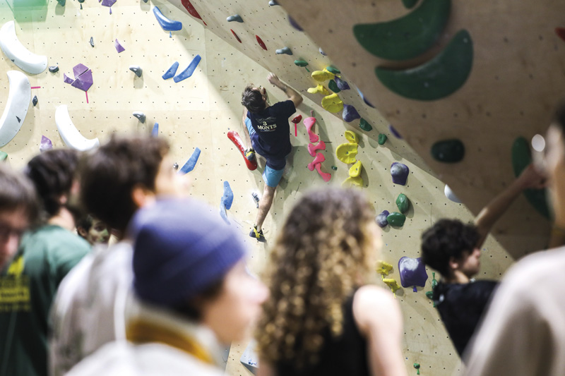 Un grimpeur parcourt le mur devant un public.