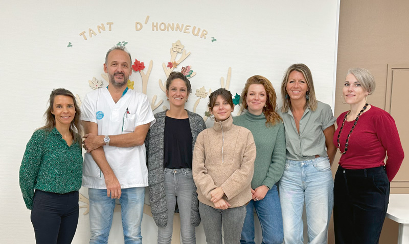 Photo de groupe. Sur le mur est écrit "Tant d'honneur".