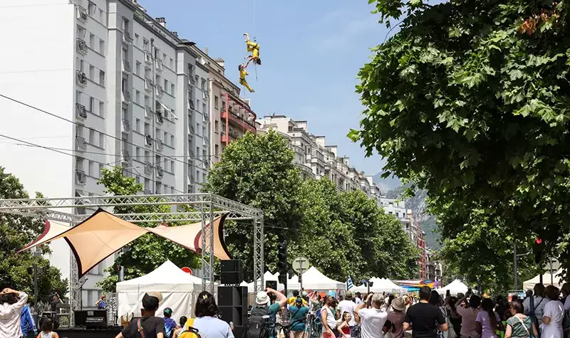 Des danseuse descendent sur un fil tendu entre deux immeubles.