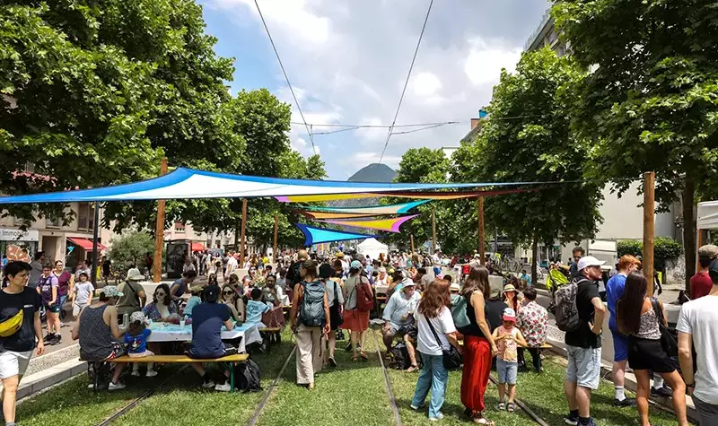 Des personnes se restaurent sur des tables installées dans l'herbe.
