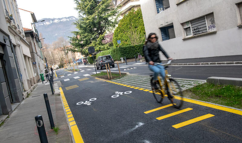 Une cycliste roule sur une piste cyclable double sens.