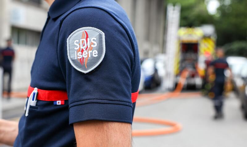Photo d'un uniforme du SDIS avec au second plan un camion d'intervention.