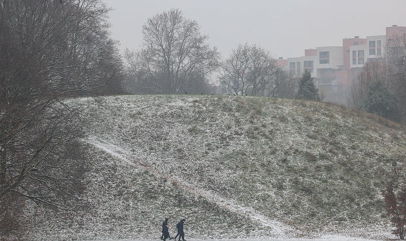Deux personnes marchent le long d'une butte enneigée.