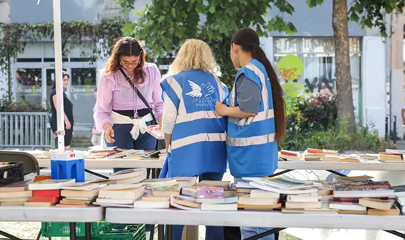 Une personne recherche des livres étalés sur une table.