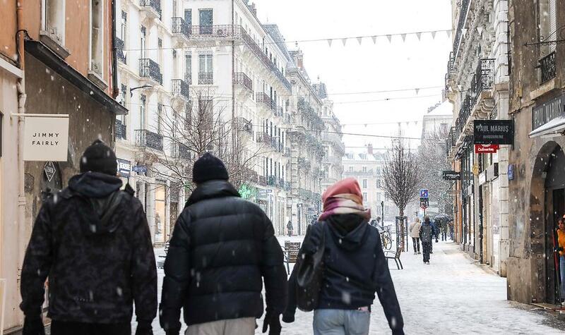 Trois amis marchent dans les rues du centre-ville. Les flocons tombent.