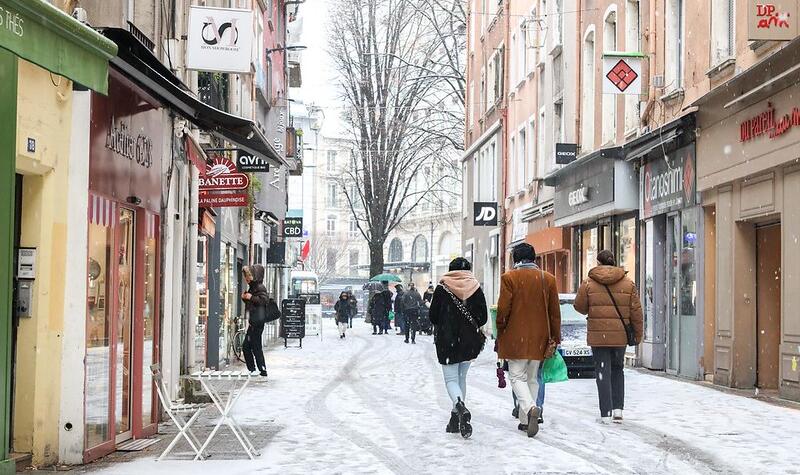 Du monde se promène dans la rue sur une fine couche de neige.
