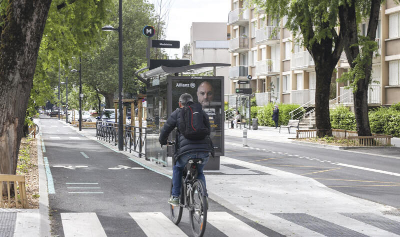 Un cycliste roule sur une piste cyclable double sens ombragée.
