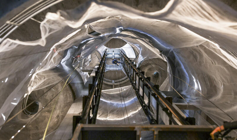 Un ouvrier est suspendu sur une corde au centre de la tour.