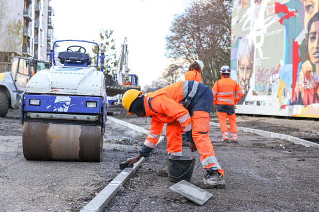 Un ouvrier travaille sur les rebords d'un futur chemin piéton.