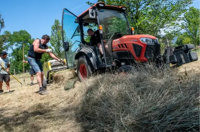 Photo d'agents de la Ville entrain de faucher du foin avec l'aide d'un tracteur.