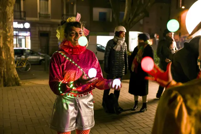 Photo d'une artiste qui jongle avec des balles lumineuses.