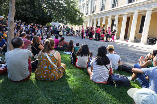 Une foule écoute une fanfare dans le jardin des Plantes.