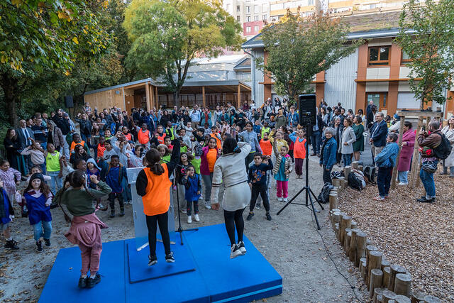 Des enfants rassemblés dans la cour dansent ensemble. 