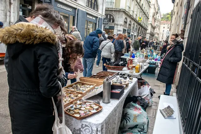 Photo de de la rue des Antiquaires avec des passants et des stands d'antiquités.