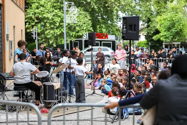 Photo d'un groupe de musique et de petits chanteurs jouant devant une assemblée d'enfants et leurs parents