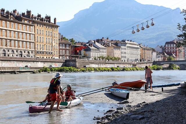 Des personnes partent faire du canoë sur l'Isère depuis les berges.