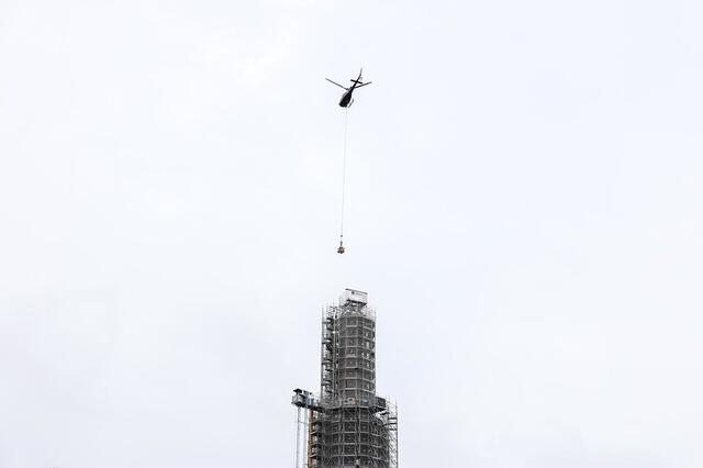 Un hélicoptère survole la Tour Perret pour y déposer la boule sommitale.